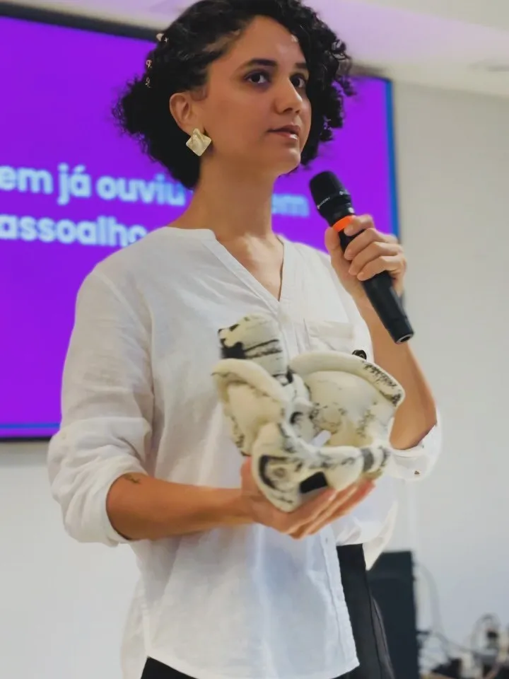 Larissa Soares apresentando um modelo anatômico da pelve em palestra
